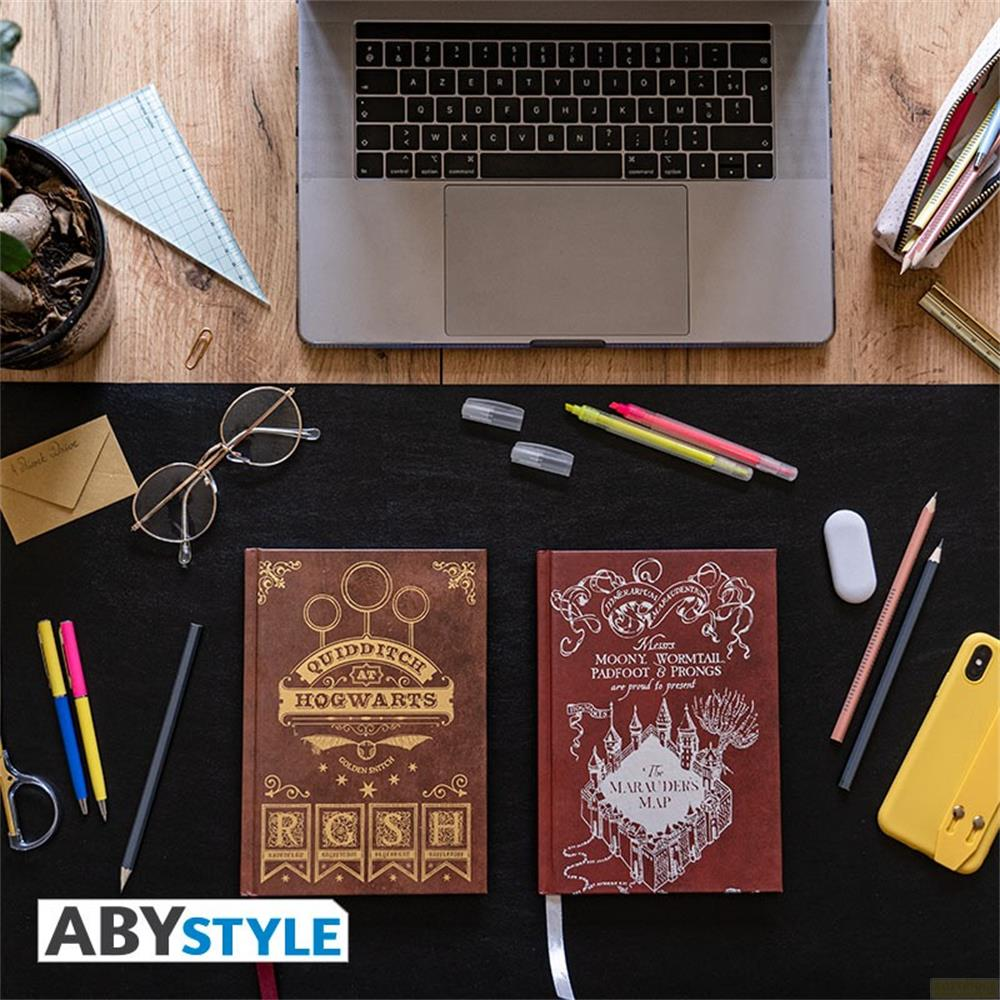 Ein Laptop, zwei Bücher, Brille, Stifte und ein Handy auf einem Holztisch.