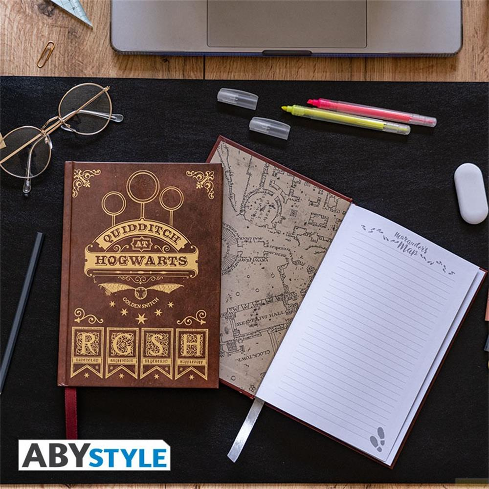 Ein Harry Potter Notizbuch mit Quidditch-Motiv, daneben eine Karte und ein leeres liniertes Notizbuch.