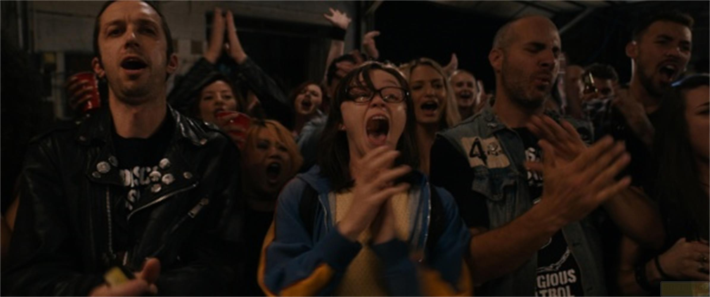Una folla di persone acclama e applaude a un evento.