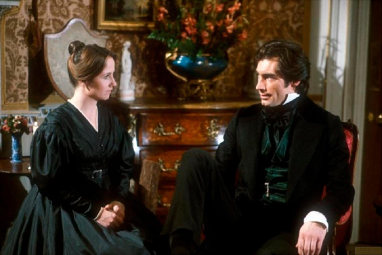 Una donna in abito nero e un uomo in abito nero sono seduti uno di fronte all'altro.