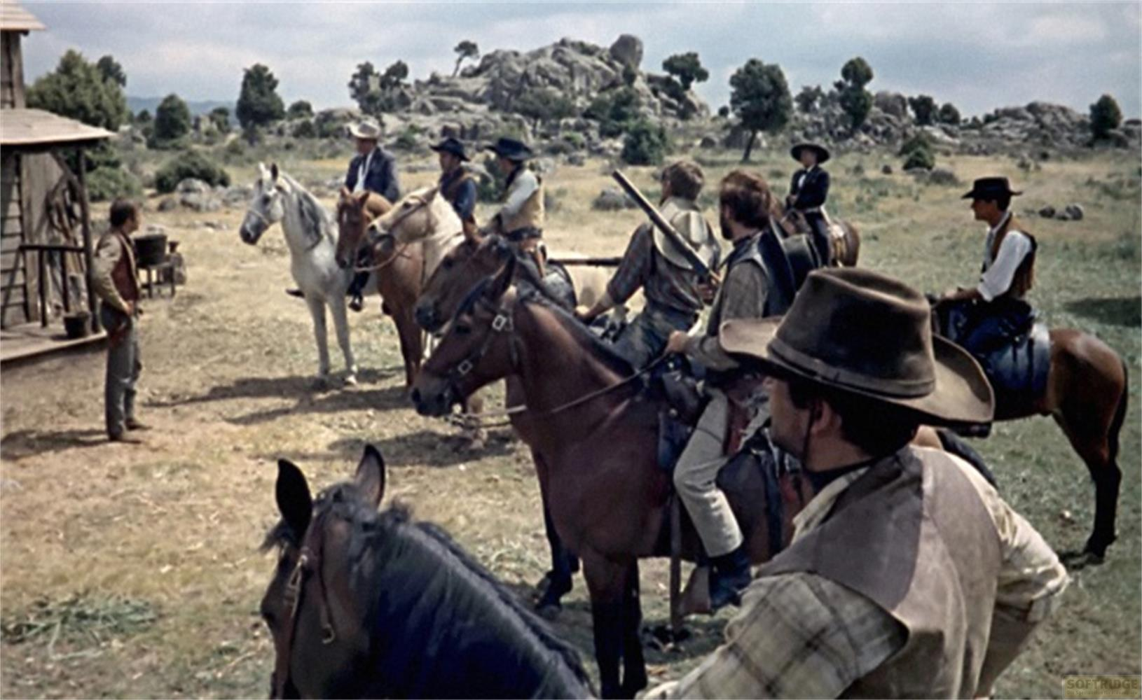 Uomini in abiti da cowboy a cavallo davanti a un edificio nel West.