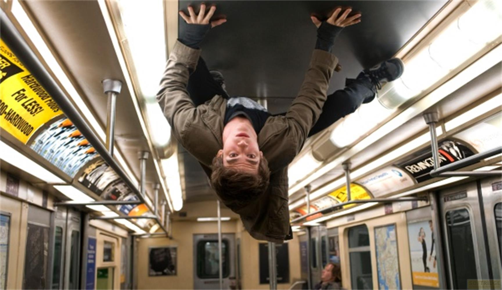 Un homme pend à l'envers dans un train, agrippé au plafond.