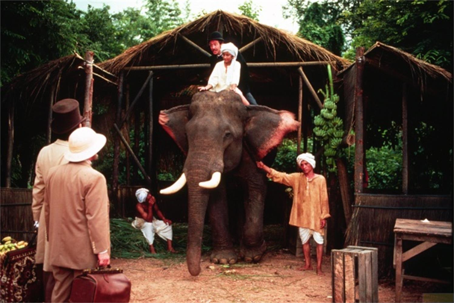 Un elefante sotto un tetto di paglia con cavalieri e addestratori.