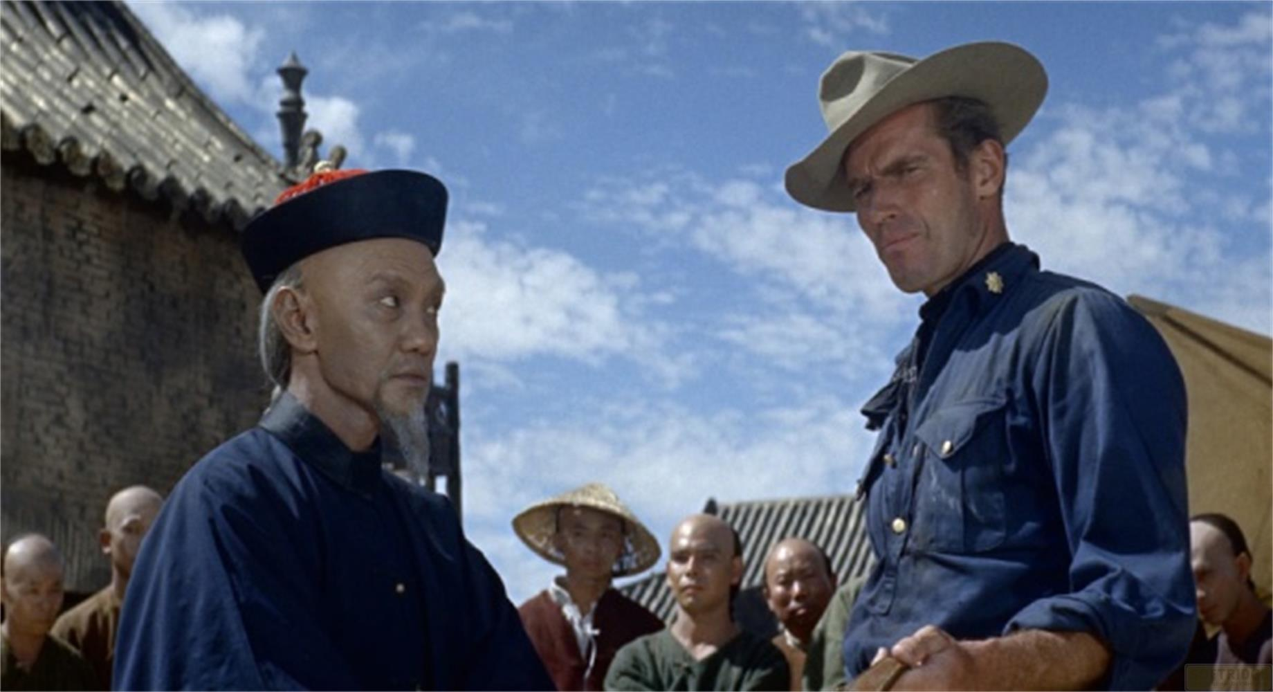 Un homme en chapeau de cowboy parle à un homme asiatique en tenue traditionnelle.