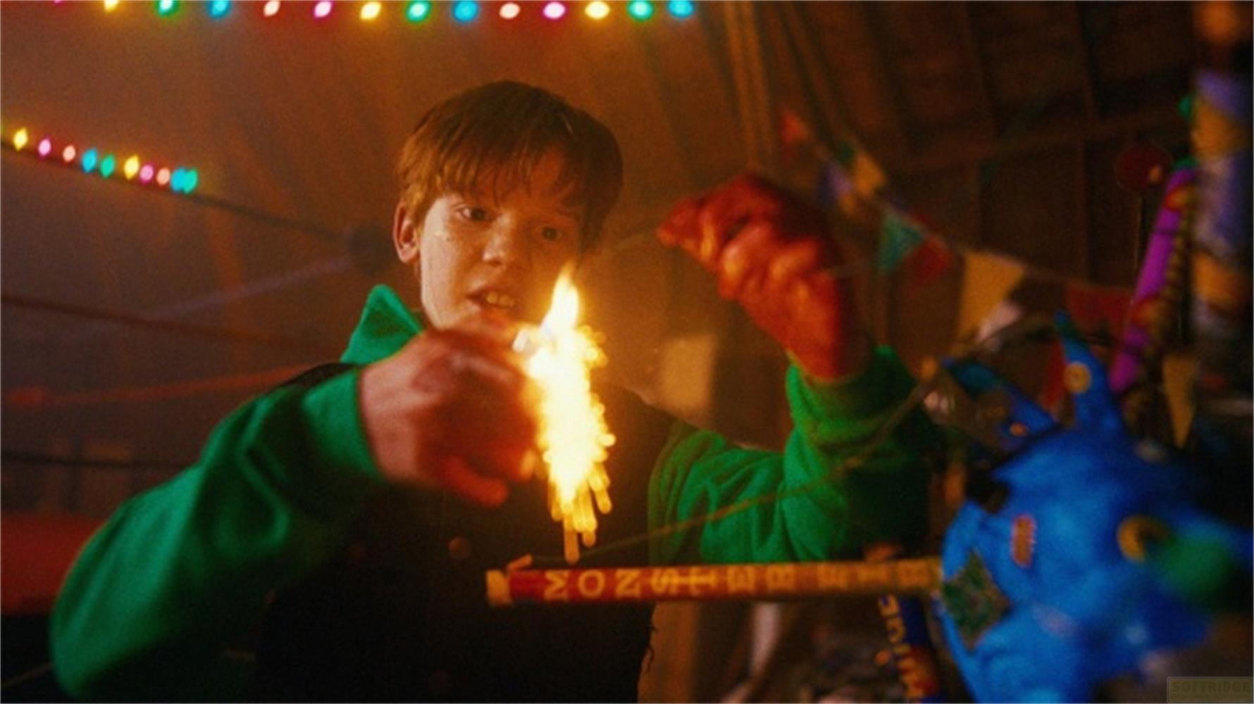 Un ragazzo accende un petardo davanti a luci colorate.