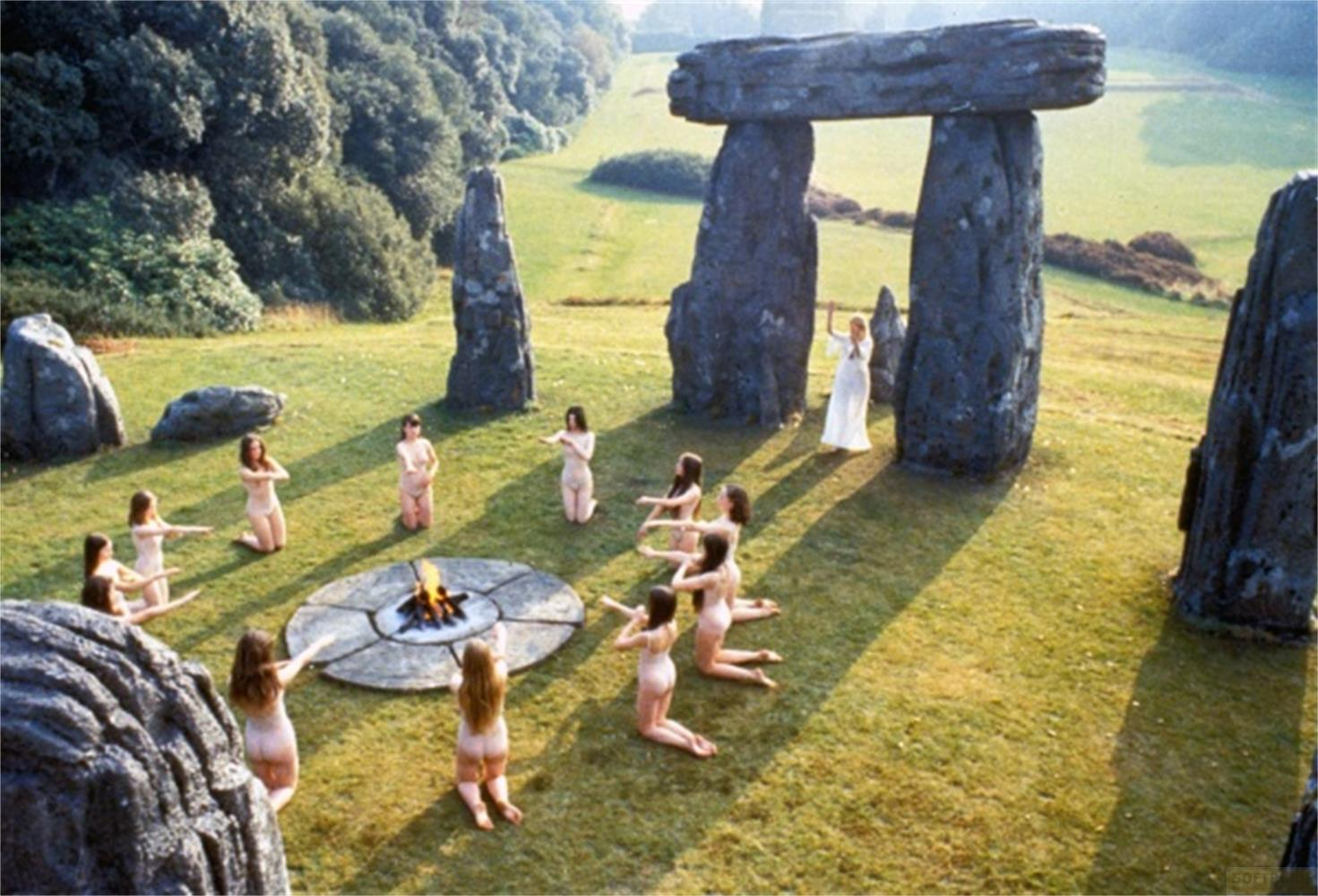 Donne in vesti bianche danzano attorno a un fuoco a Stonehenge.