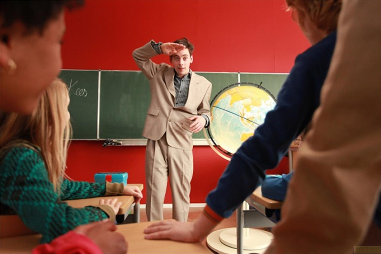 Professeur avec geste de salut regarde un globe dans une salle de classe avec des enfants.