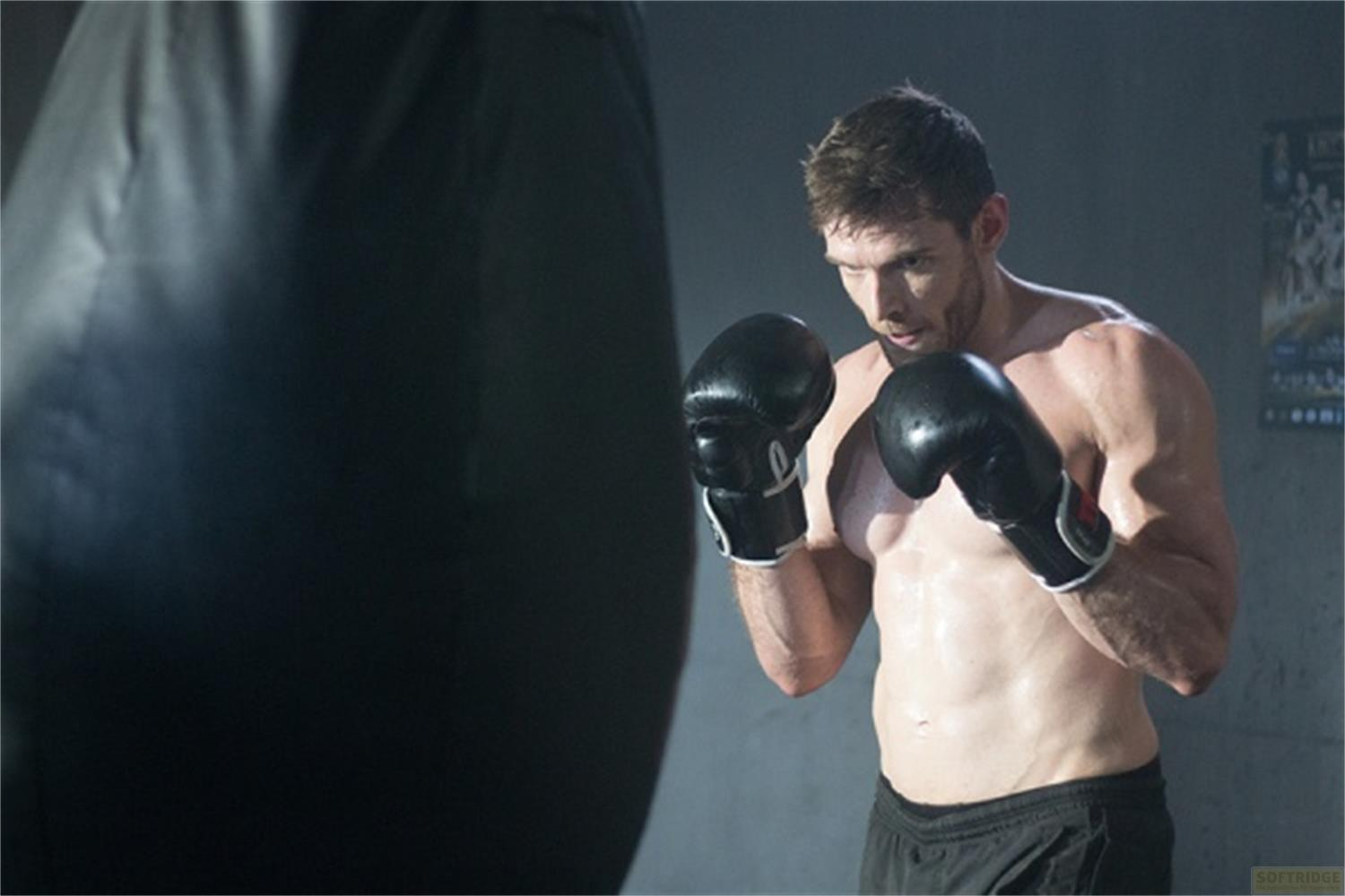 Un uomo con guantoni da boxe si allena davanti a un sacco da boxe.
