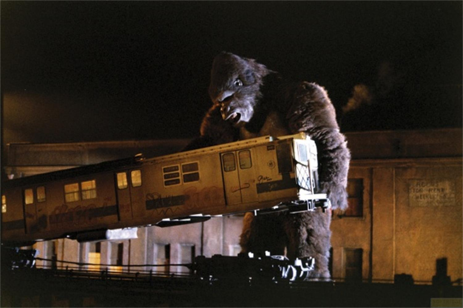 Un gorilla gigante tiene un tren de notte, con edifici sullo sfondo.