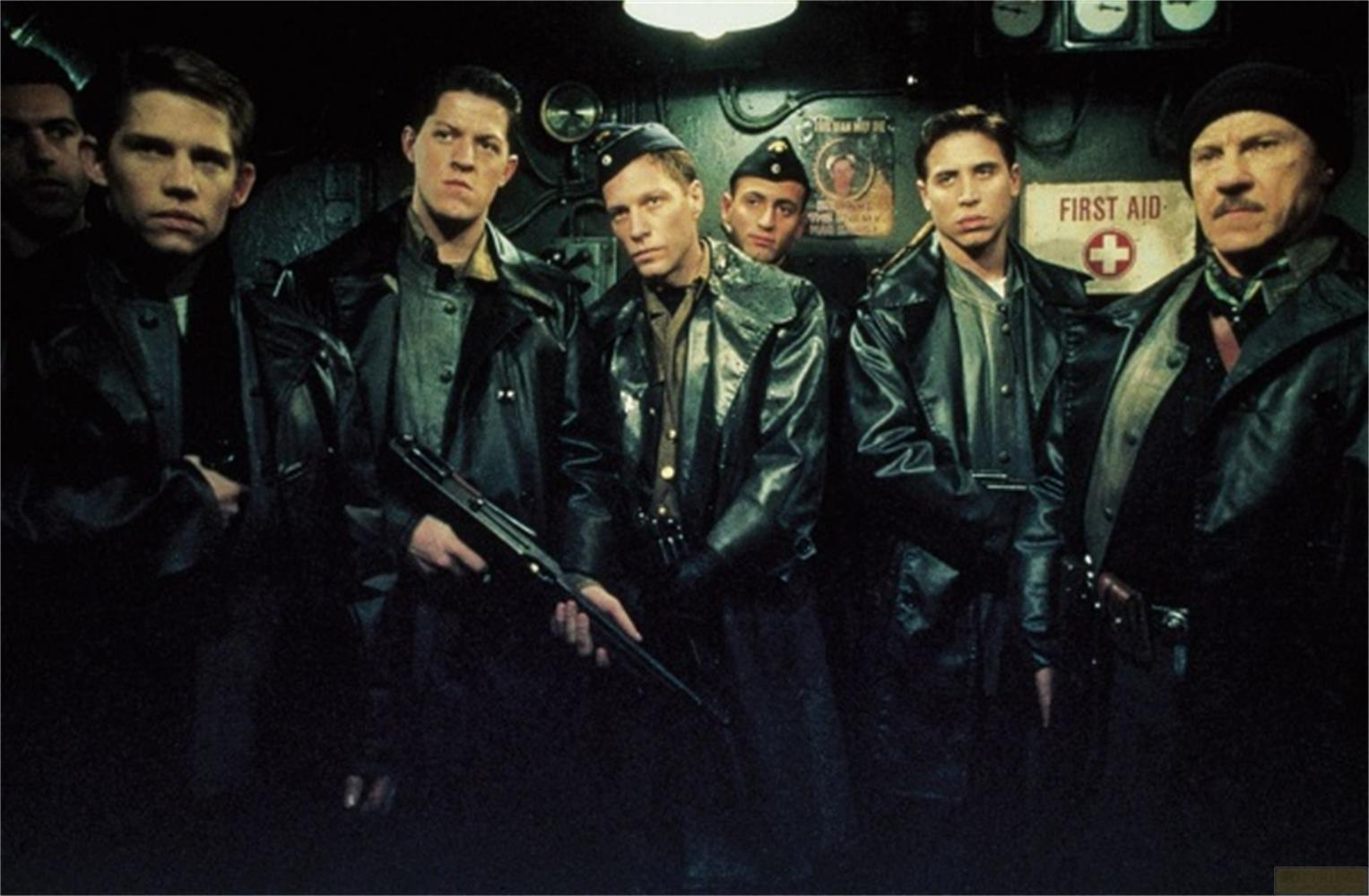 Sechs Männer in dunklen Lederjacken posieren in einem dunklen Raum. Einer hält ein Gewehr.