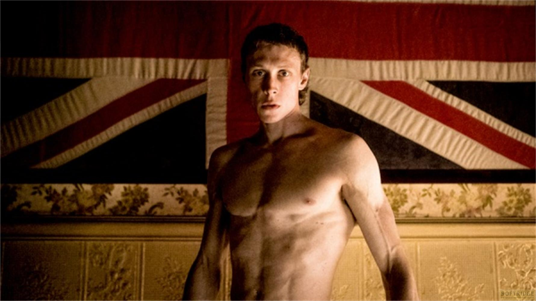 Un homme devant un drapeau de l'Union Jack, musclé, expression sérieuse.