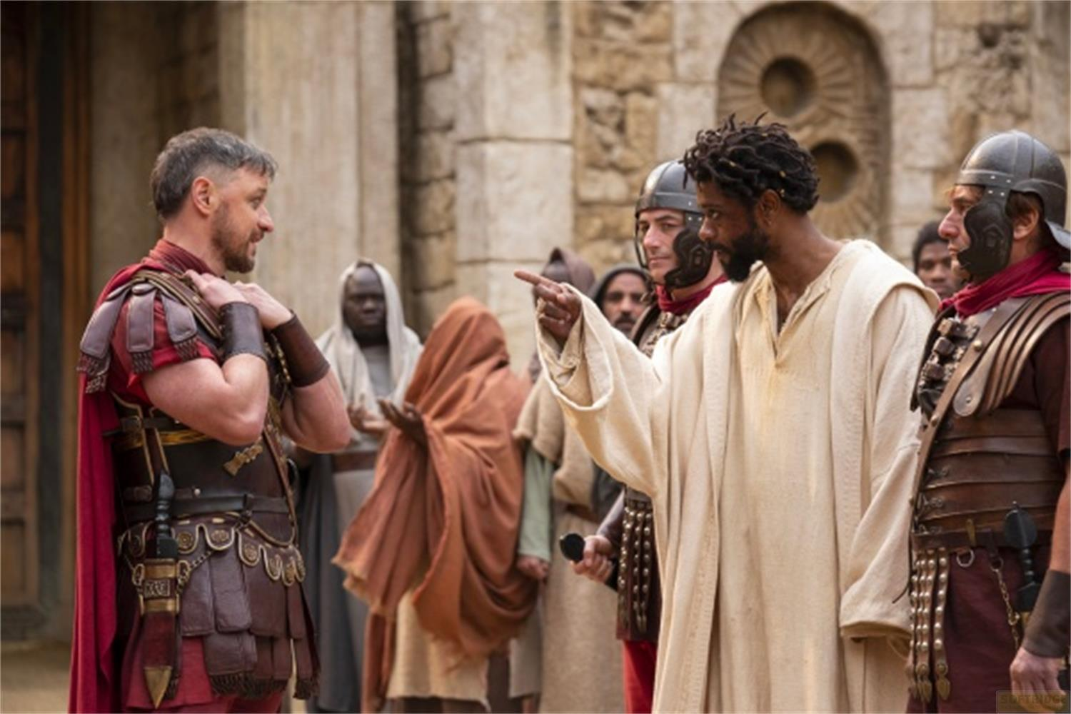Un soldato romano parla con un uomo in veste bianca, circondato da altri.