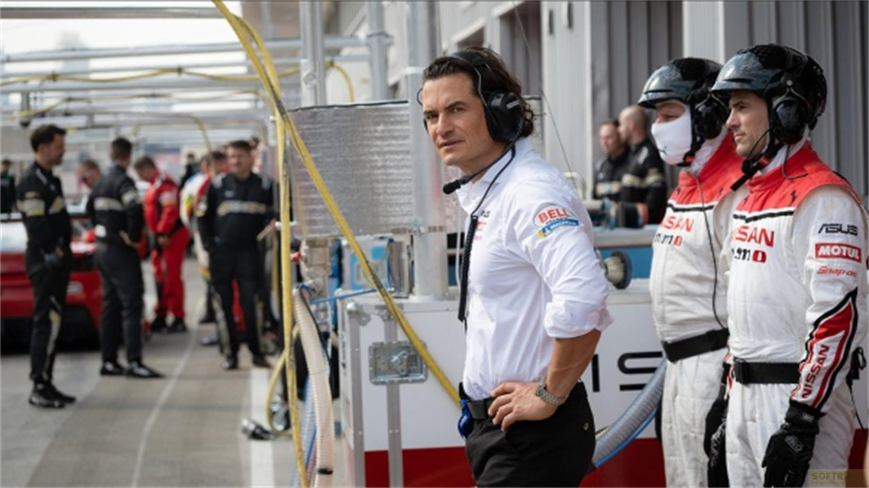 Team di corse in pit lane con uomo in camicia bianca e cuffie.