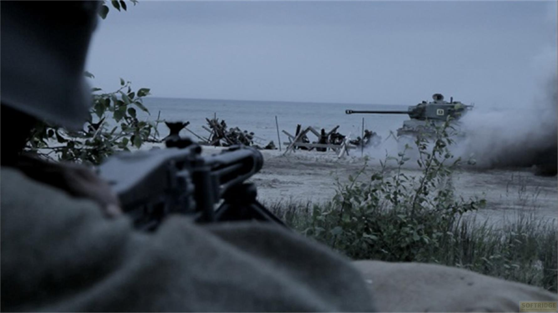 Soldat blickt durch ein Maschinengewehr auf einen Panzer am Strand.