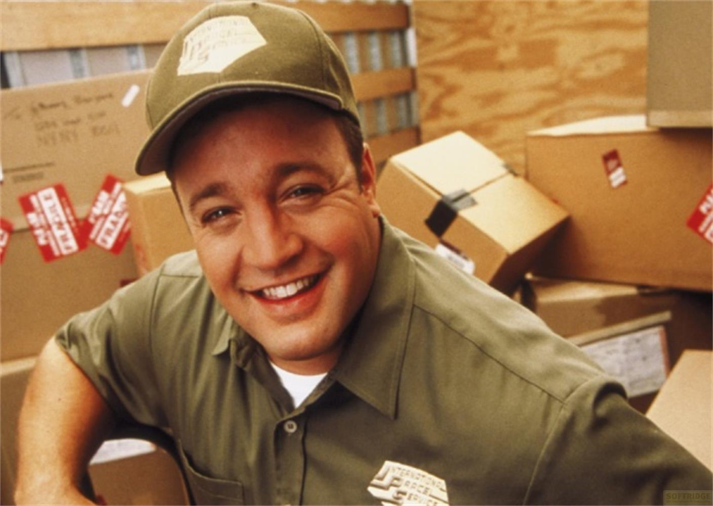 Un homme souriant en uniforme pose devant des boîtes empilées.