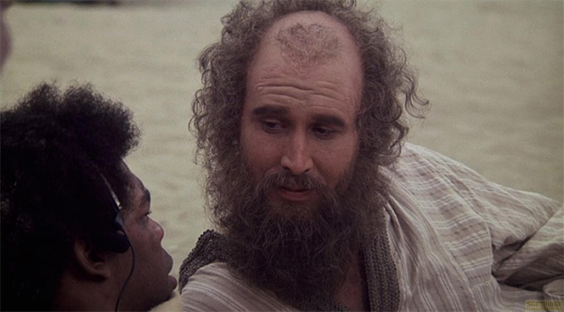 Un uomo con barba e capelli ricci parla con un uomo afro.