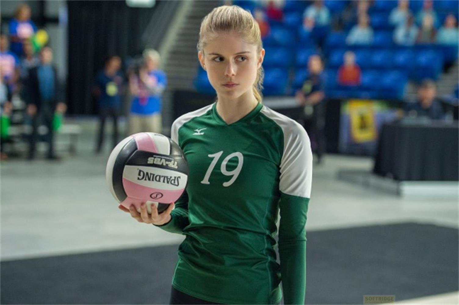 Una ragazza in maglia verde numero 19 tiene una pallavolo.