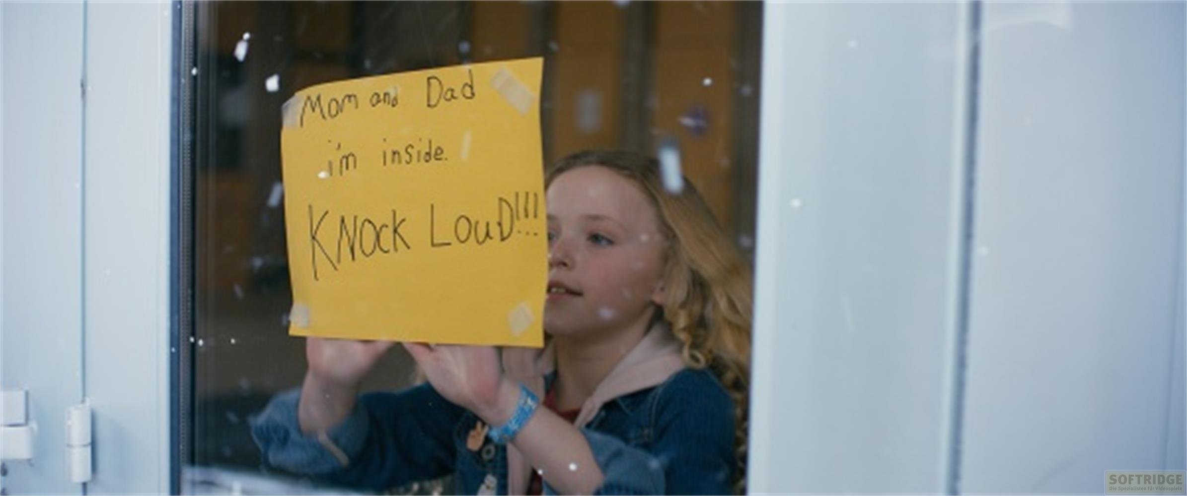 Una bambina tiene un cartello giallo con scritto "Mamma e papà sono dentro. Bussate forte!"