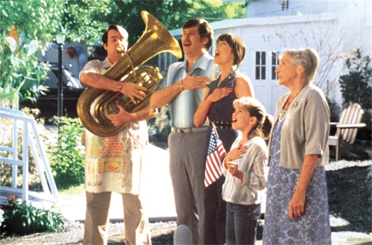 Un uomo suona la tuba mentre quattro persone tengono una bandiera americana e cantano.