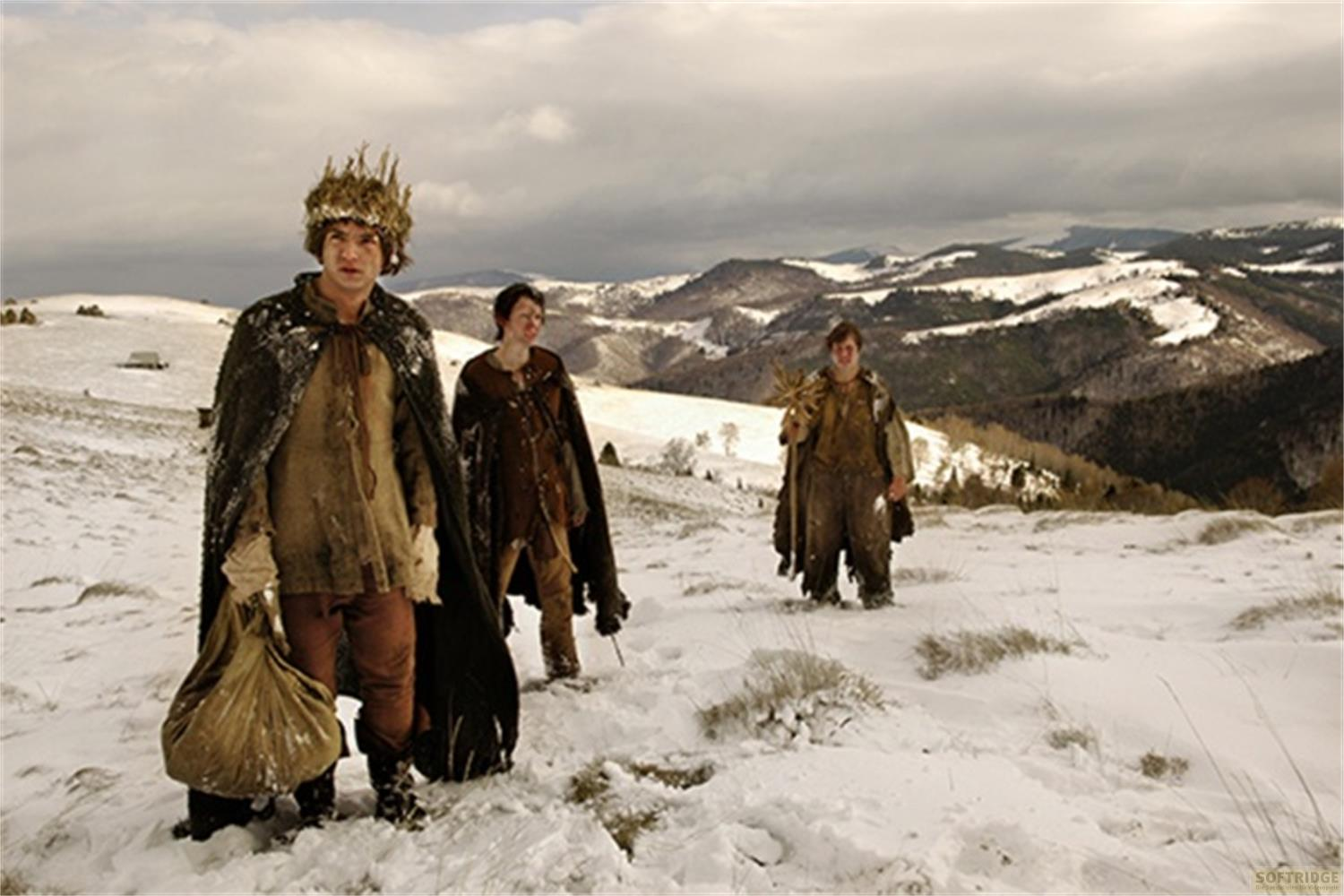 Tre uomini in abiti invernali con mantelli in un paesaggio innevato.