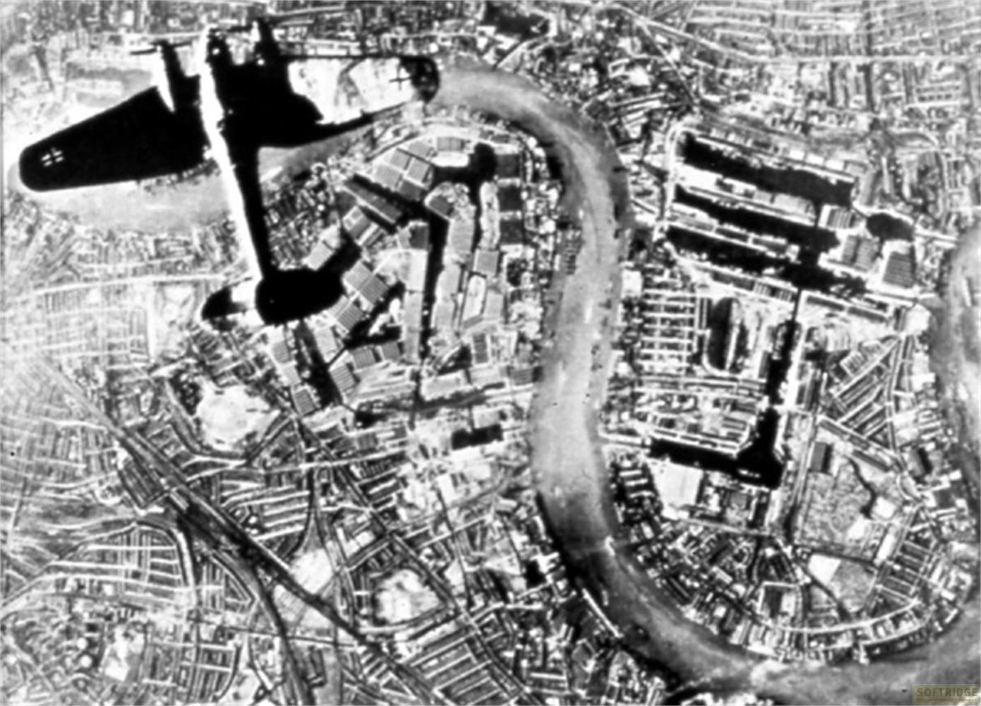 Vista aerea di una città con fiume e ombra di aereo.