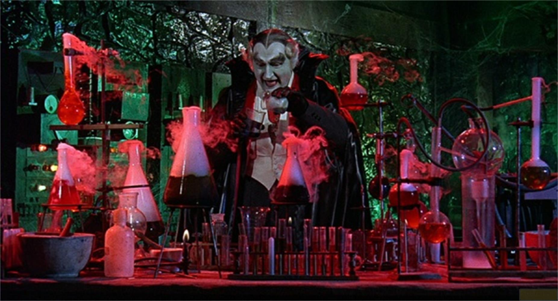 Un uomo in costume da vampiro conduce un esperimento in un laboratorio pieno di fiaschi e fumo.