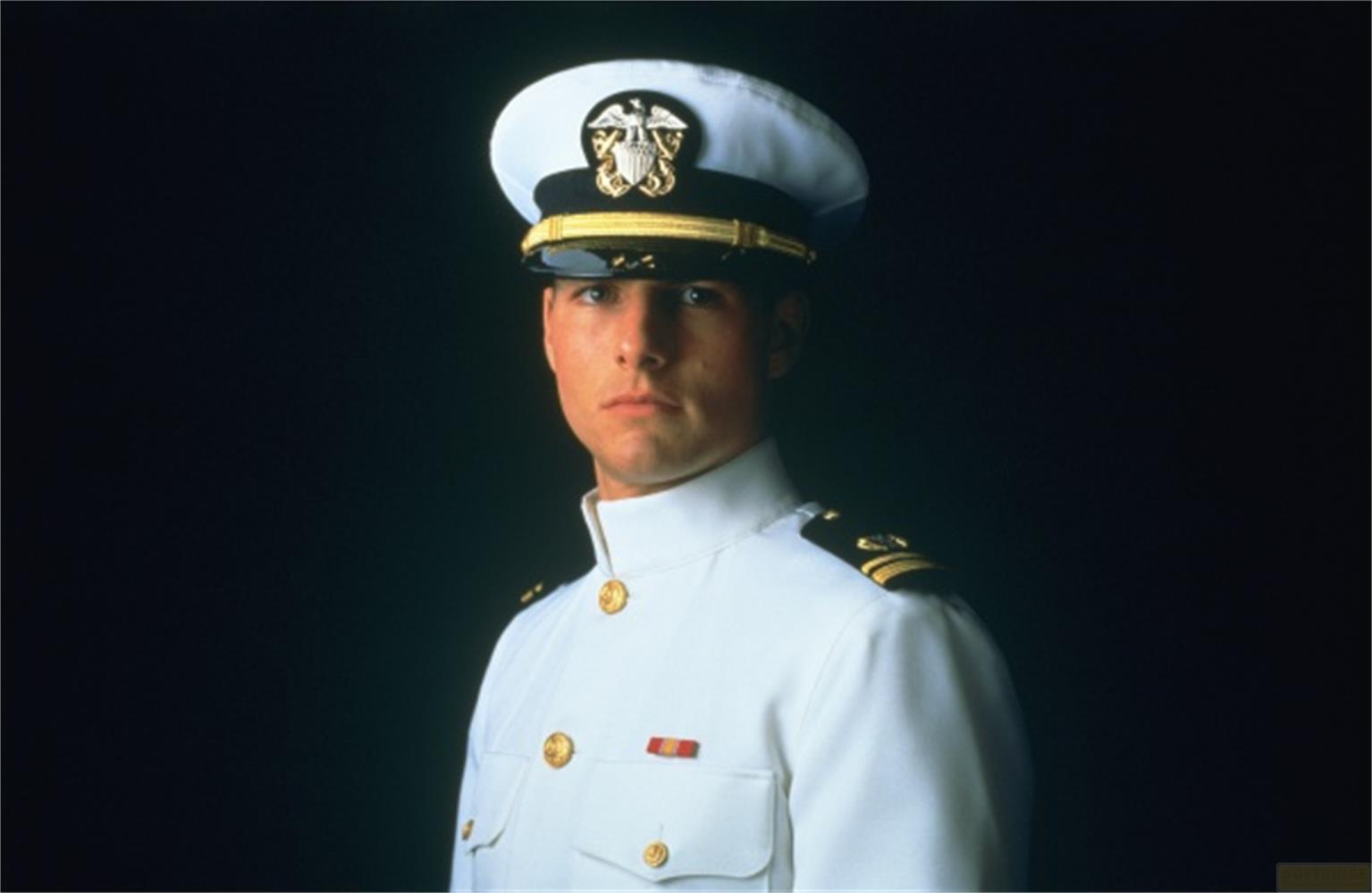 Un homme en uniforme avec chapeau et épaulettes sur fond sombre.