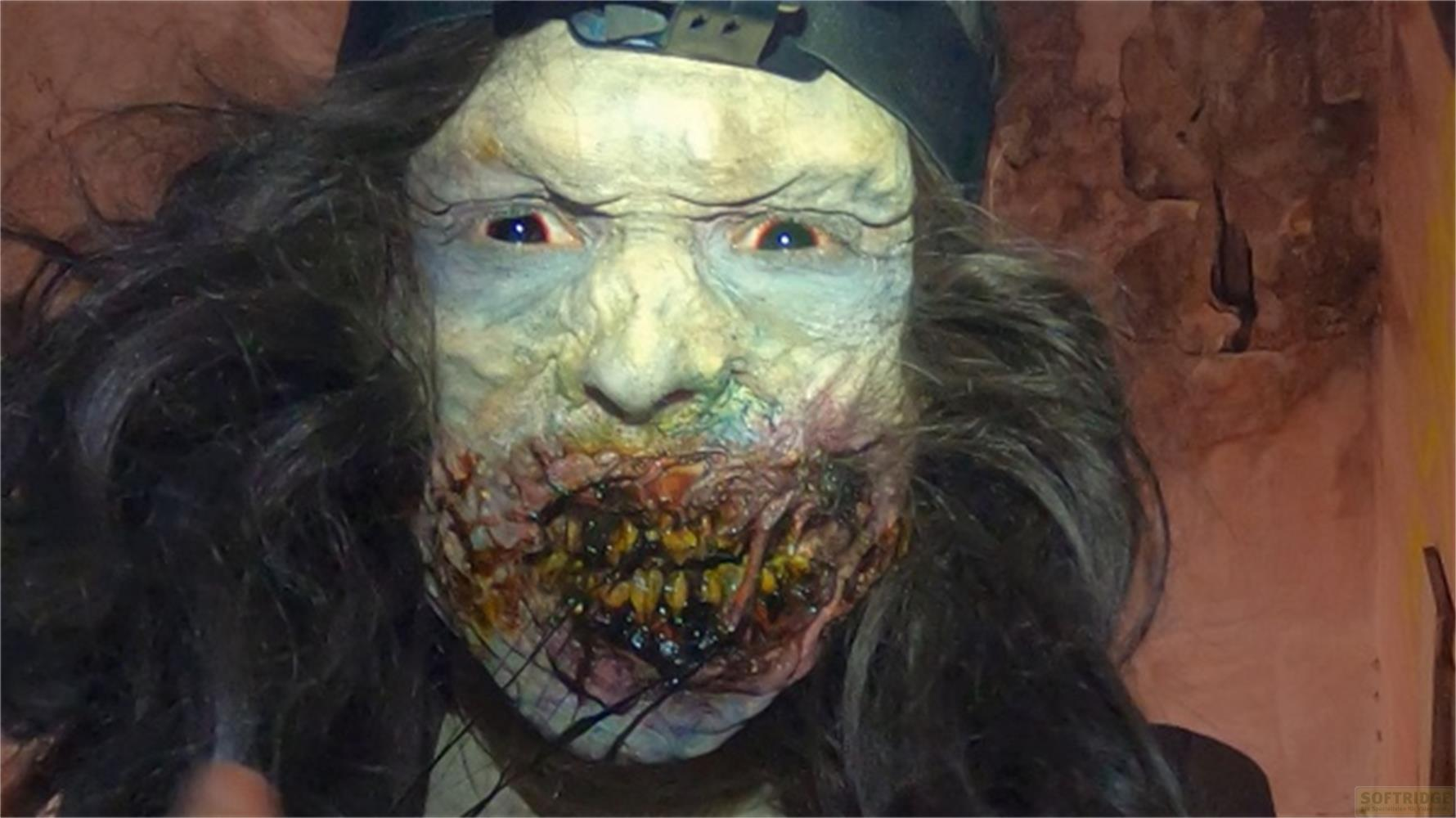 Primo piano di una maschera da zombie inquietante con lunghi capelli e viso pallido.