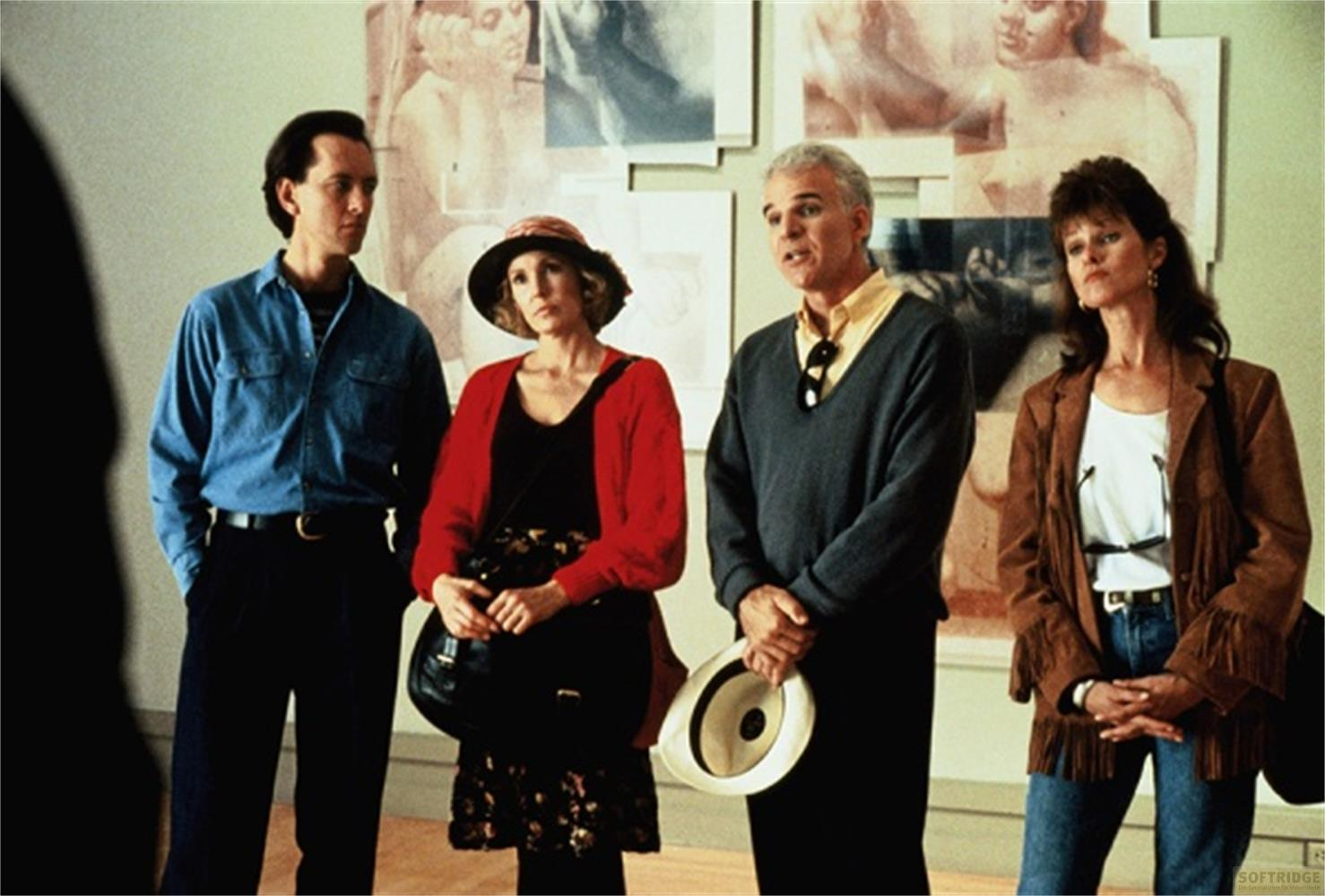 Quattro persone davanti ad opere d'arte. Un uomo in blu, una donna in rosso, un uomo in grigio e una donna in marrone.