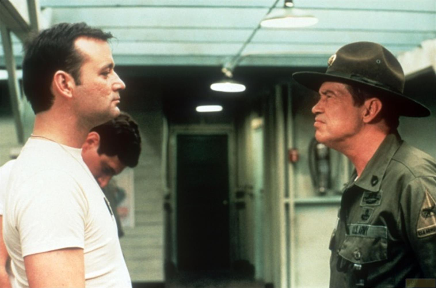 Deux soldats dans un couloir. L'un en t-shirt blanc, l'autre en uniforme avec un chapeau.
