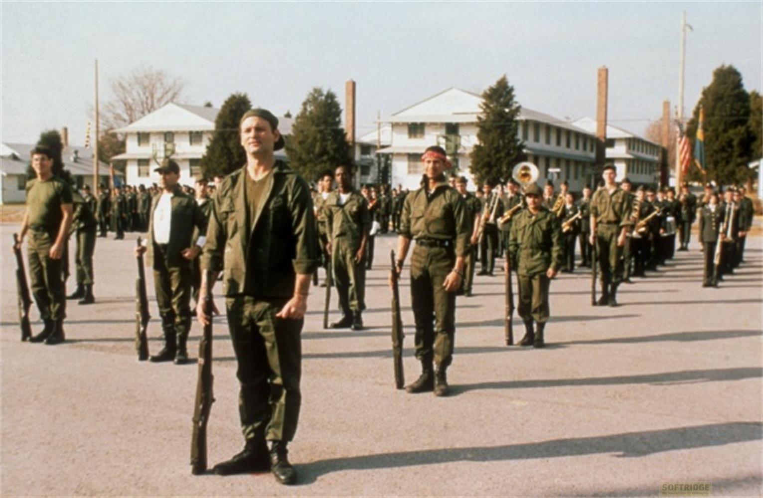 Des soldats en uniforme se tiennent dehors devant des bâtiments, certains tenant des fusils.