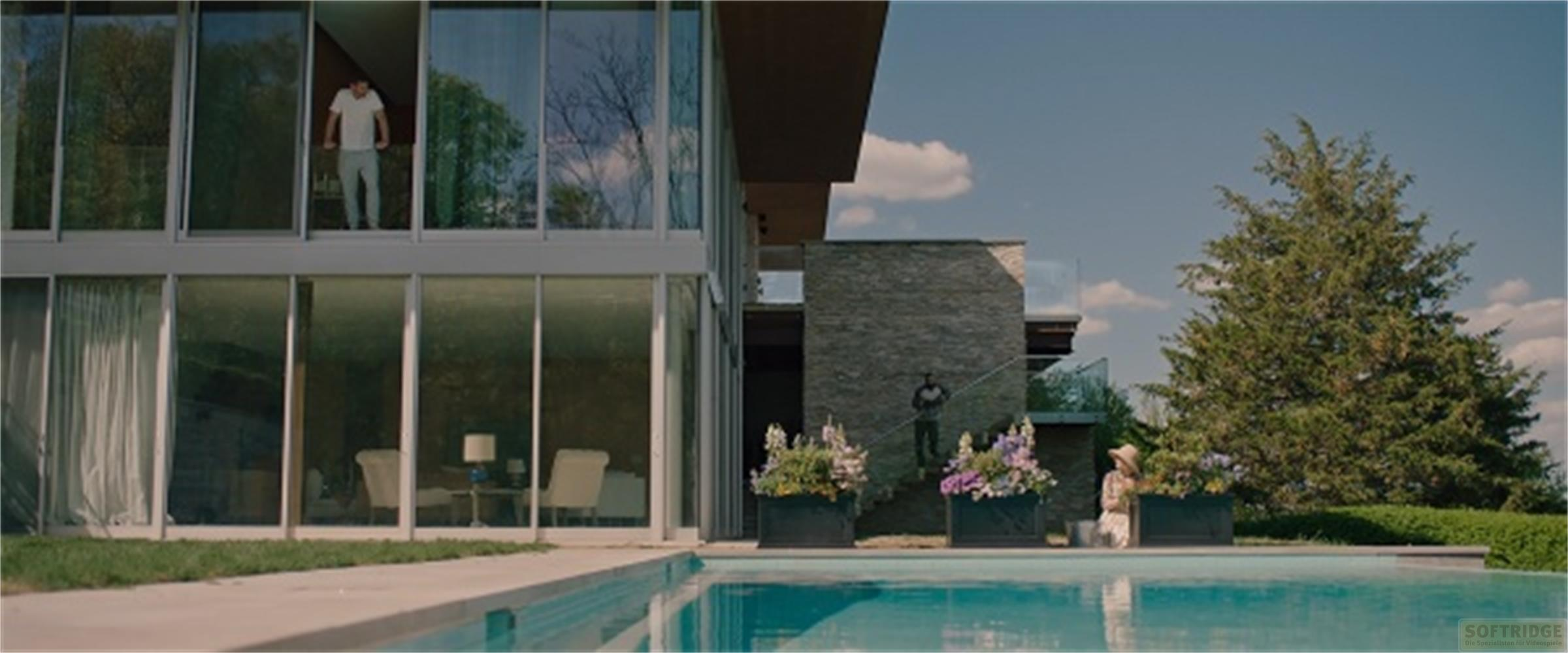 Un uomo si trova nella finestra superiore di una casa moderna. Una piscina è in primo piano.