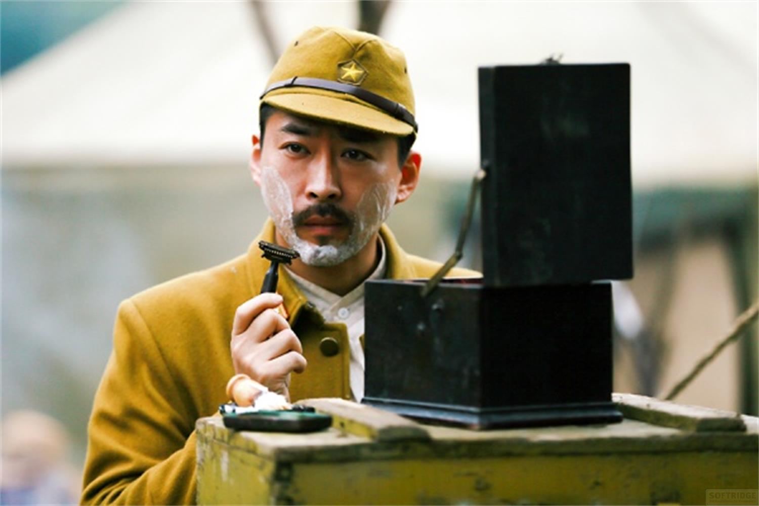 Un uomo in uniforme si rade all'aperto con un rasoio, davanti a uno specchio.