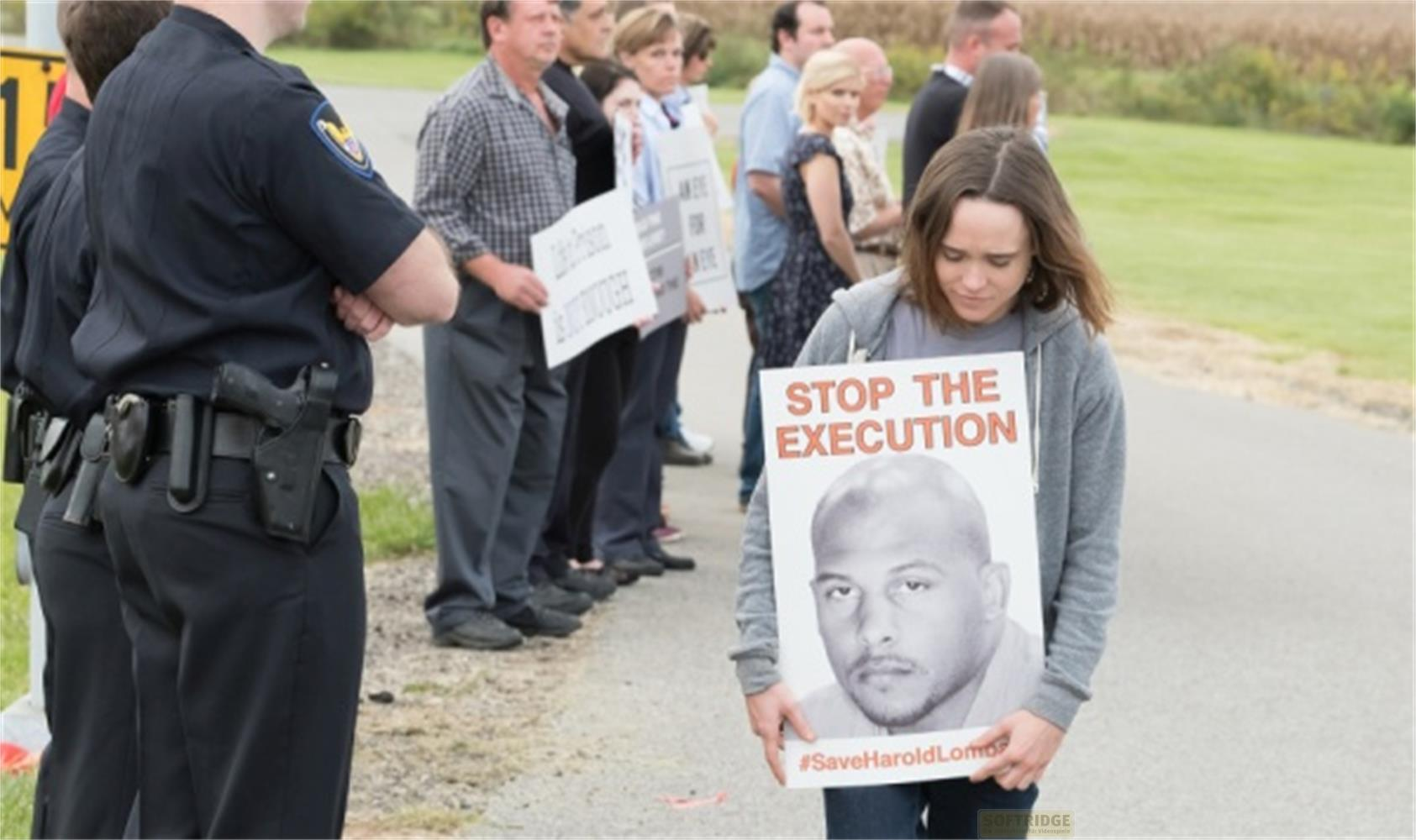 Una donna tiene un cartello con scritto "STOP THE EXECUTION" e la foto di un uomo.