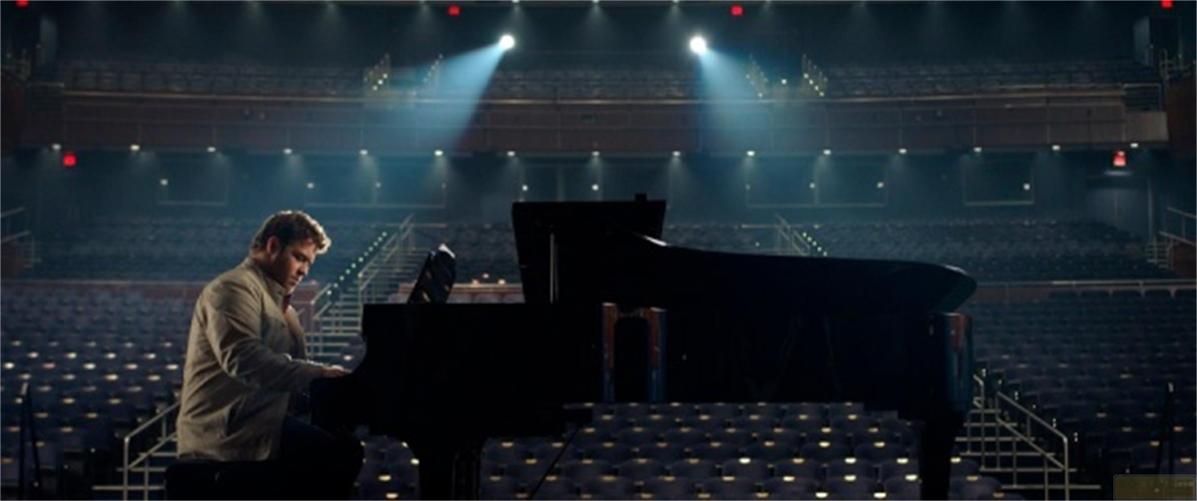 Un uomo suona il pianoforte sul palco davanti a un auditorium vuoto.