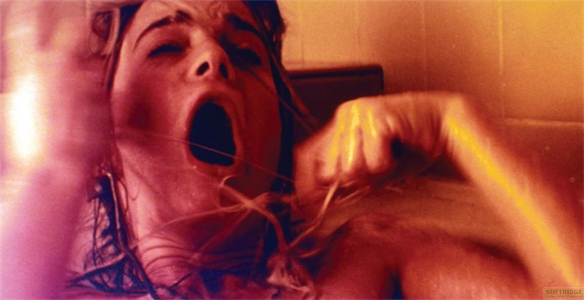 Primo piano di una donna con la bocca aperta, colori vivaci, sfondo sfocato.