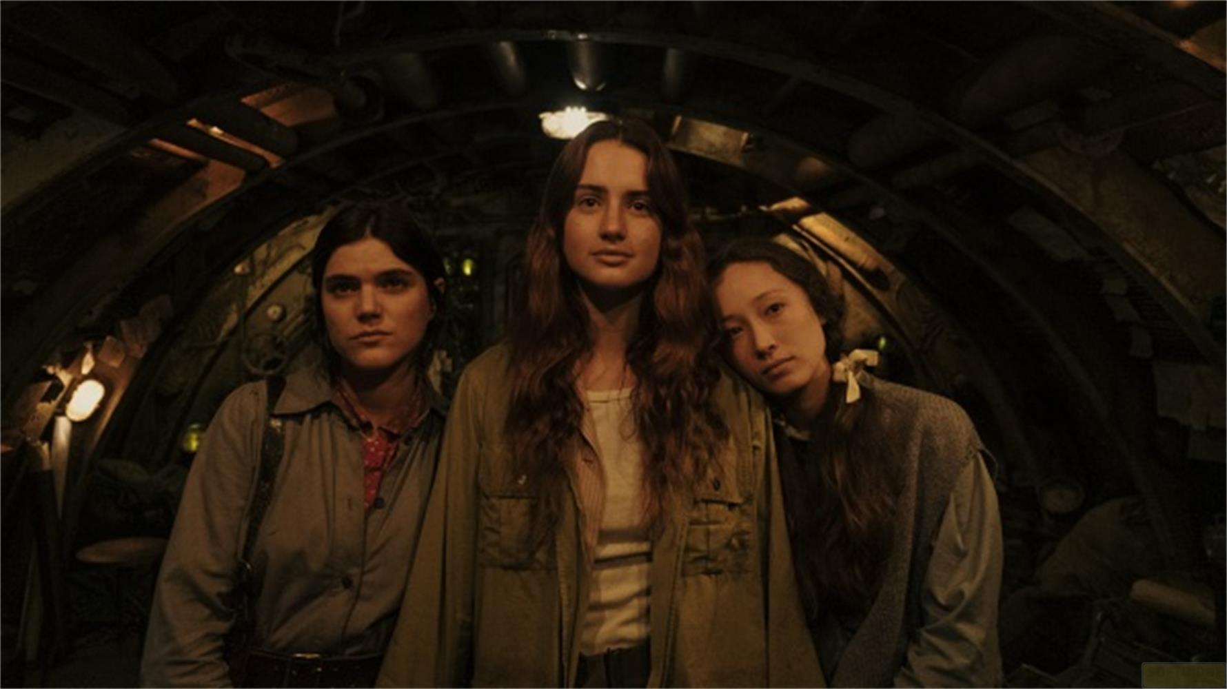 Tre donne stanno insieme in una stanza buia e tubolare con luci.