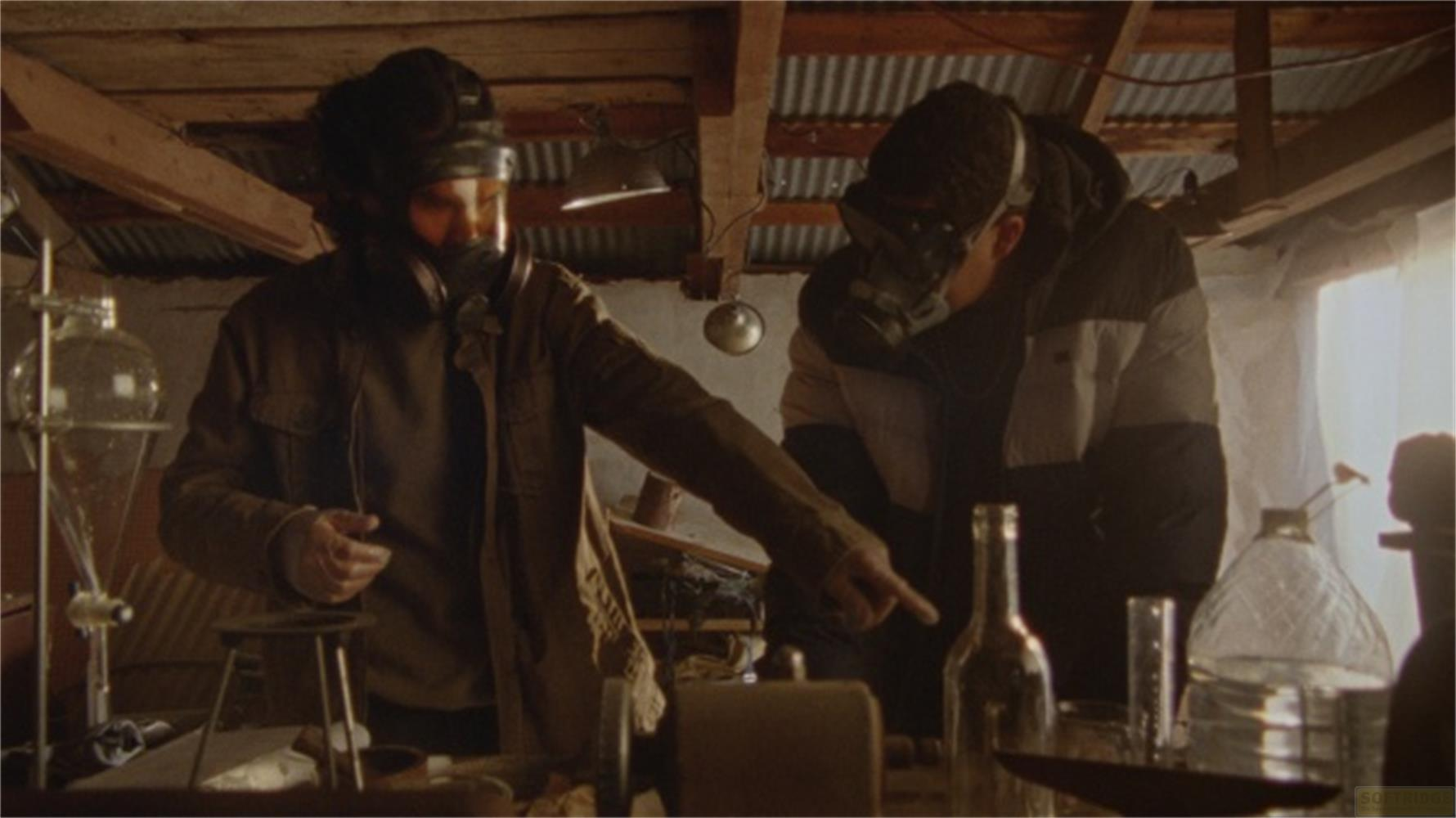 Due uomini con maschere antigas lavorano in un laboratorio con vetreria e bottiglie.