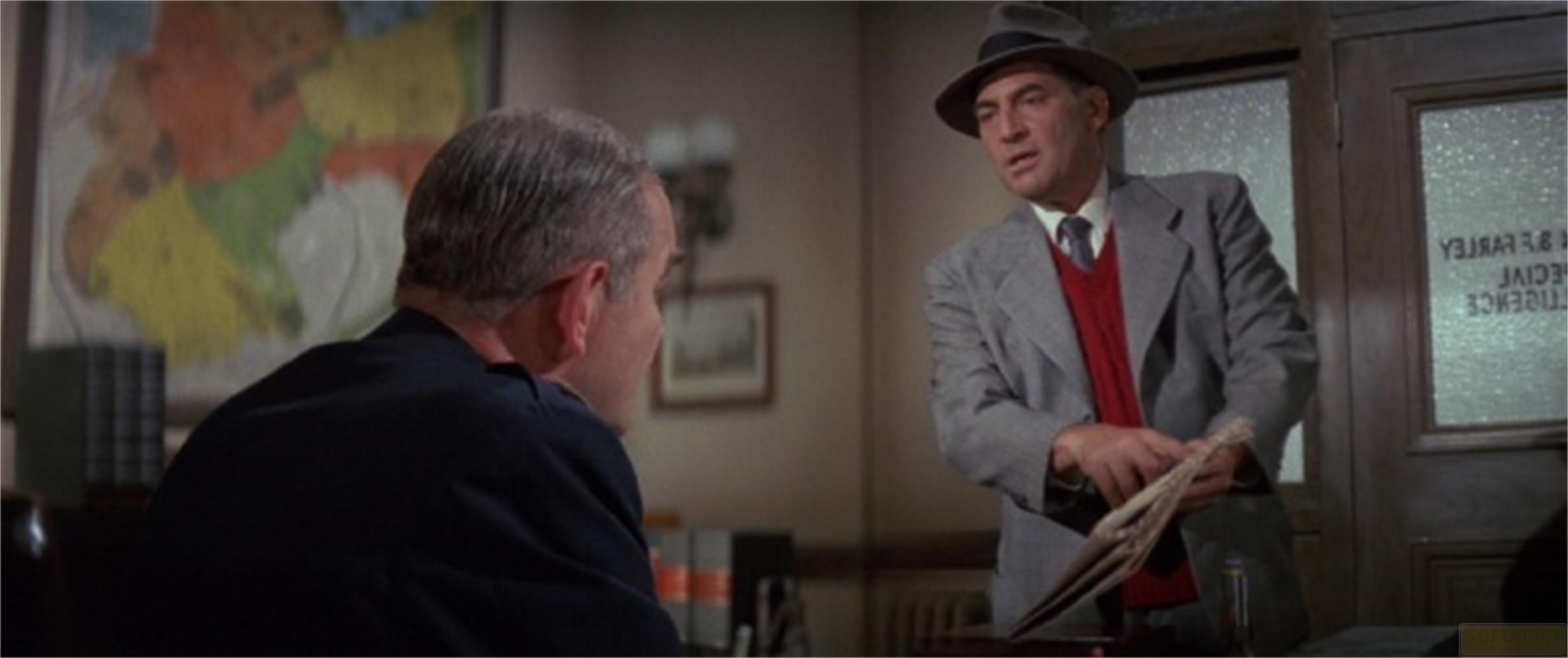 Un homme avec un chapeau parle à un autre homme dans un bureau avec une carte.
