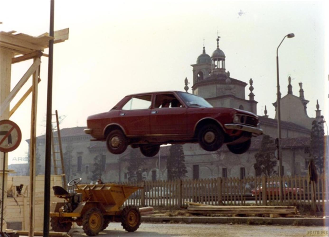 Ein rotes Auto fliegt über eine Baustelle mit einem Minibagger.