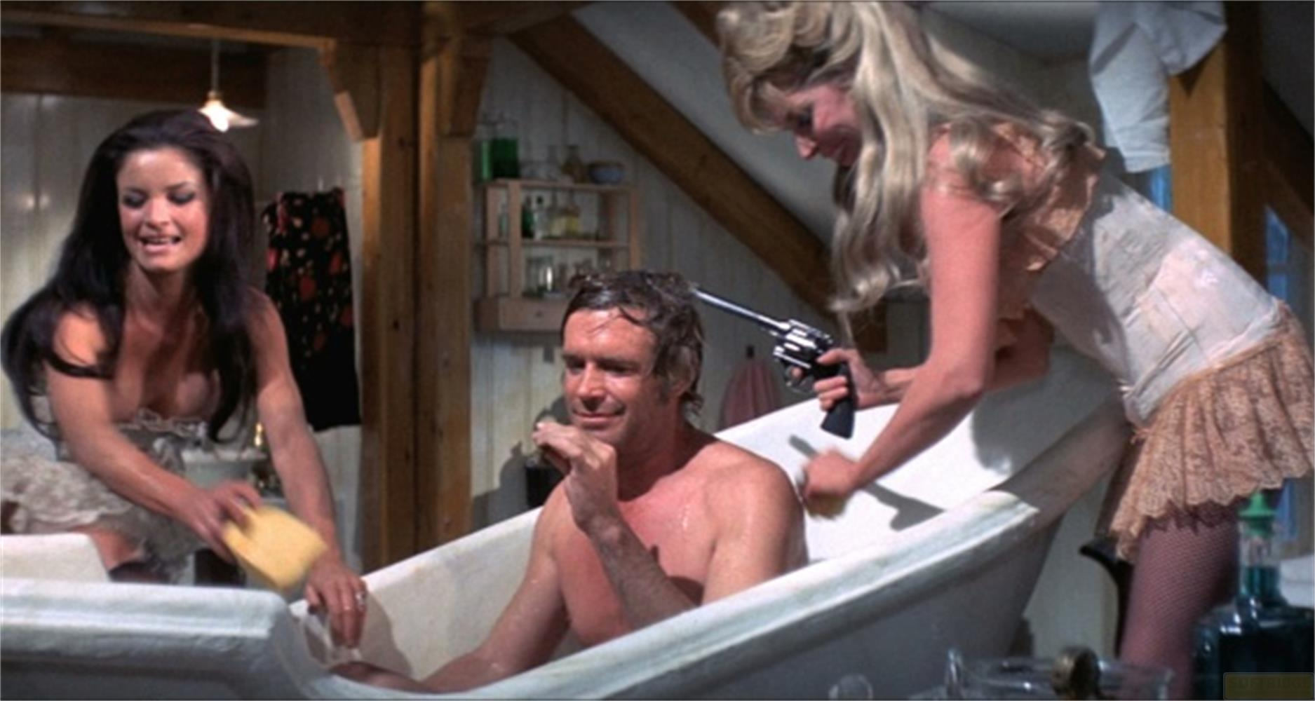 Due donne in un bagno con un uomo in una vasca da bagno, una tiene una pistola.