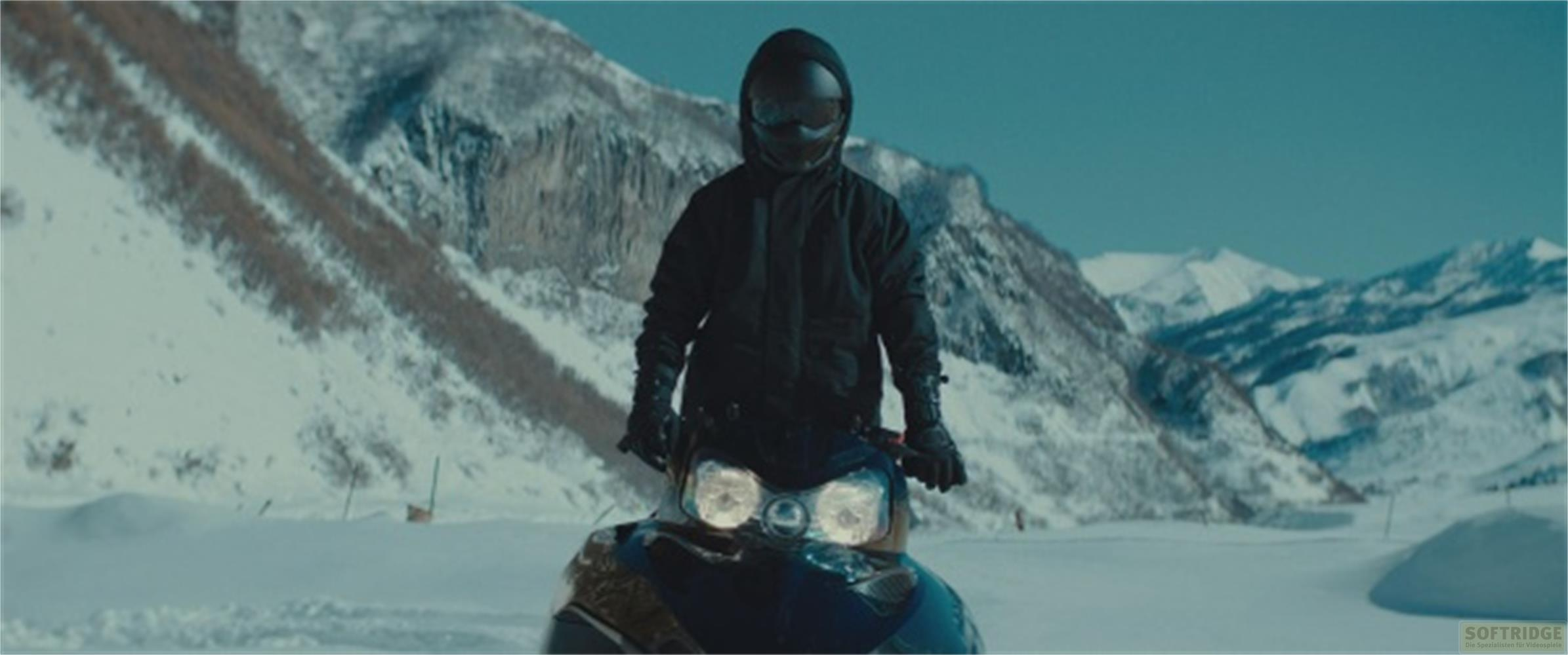 Persona in abiti neri su motoslitta in un paesaggio montano innevato.