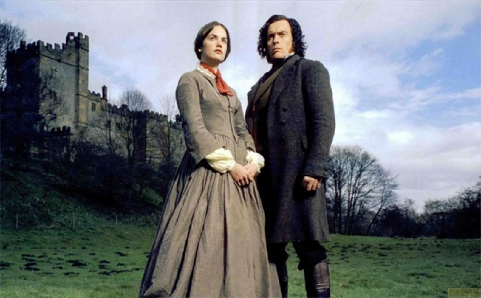 Un uomo e una donna stanno davanti a un castello. La donna indossa un vestito, l'uomo un cappotto.