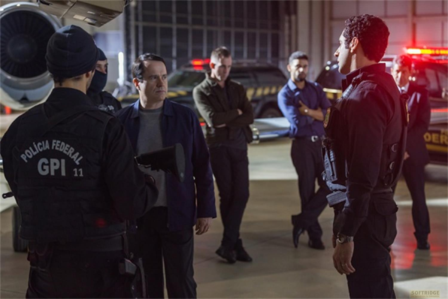Gruppo di uomini in uniforme e abiti civili in un hangar vicino a un aereo.