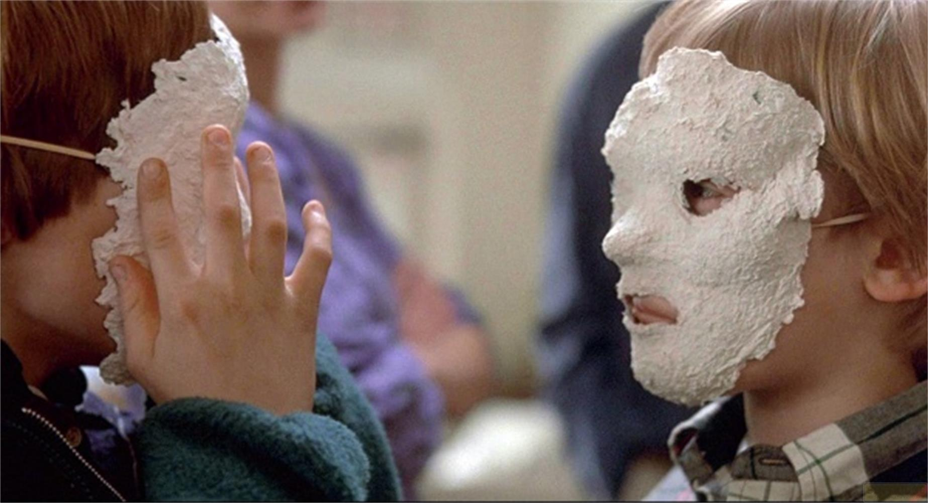 Due bambini indossano maschere di cartapesta bianche che coprono i loro volti.