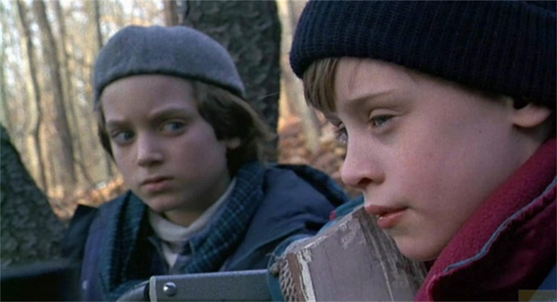 Due ragazzi in abiti invernali in un bosco, uno indossa un berretto, l'altro un basco.