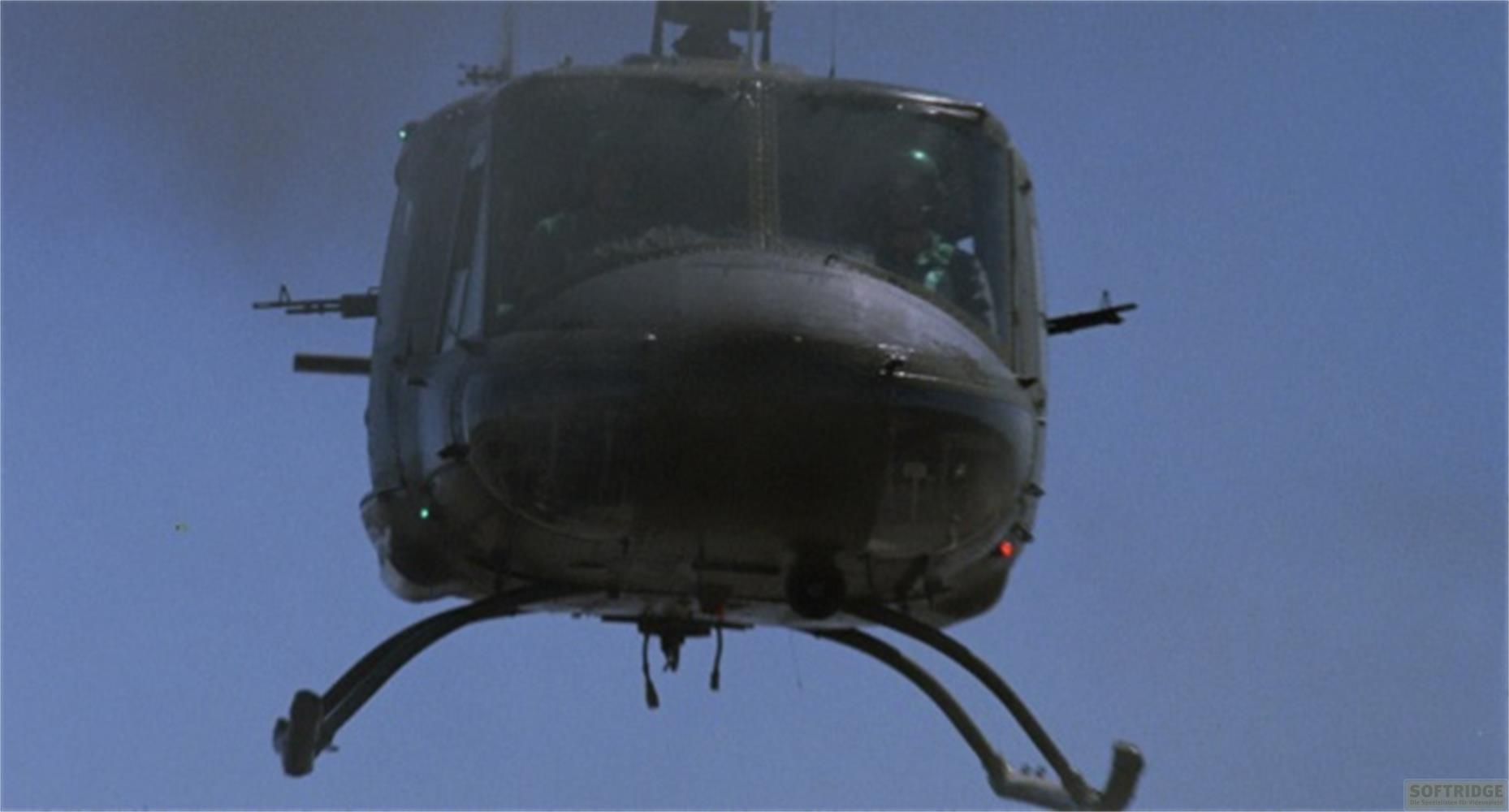 Ein dunkler Hubschrauber fliegt im Vordergrund vor blauem Himmel.