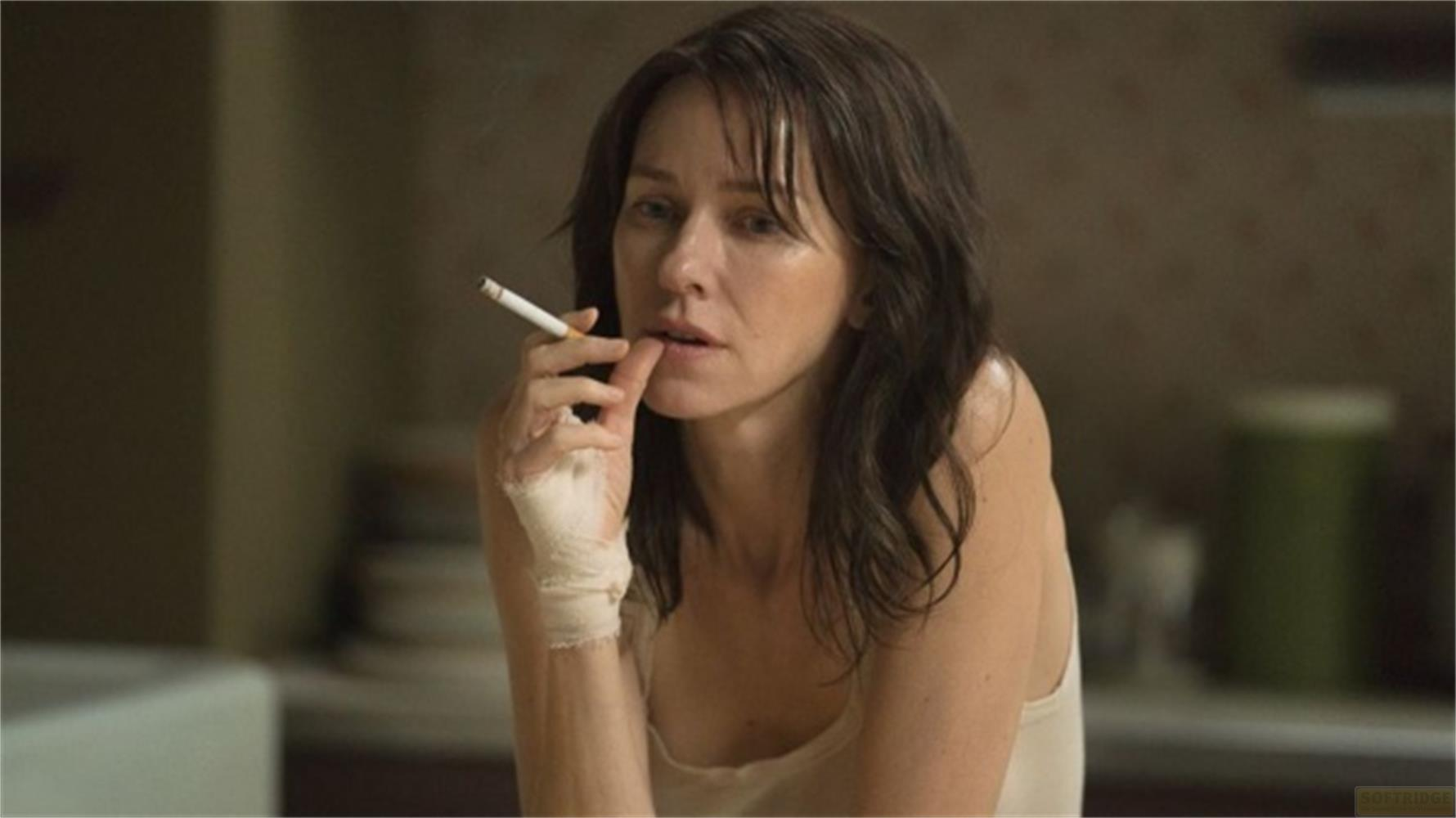 Una donna con un braccio fasciato fuma una sigaretta, il dito sulle labbra.