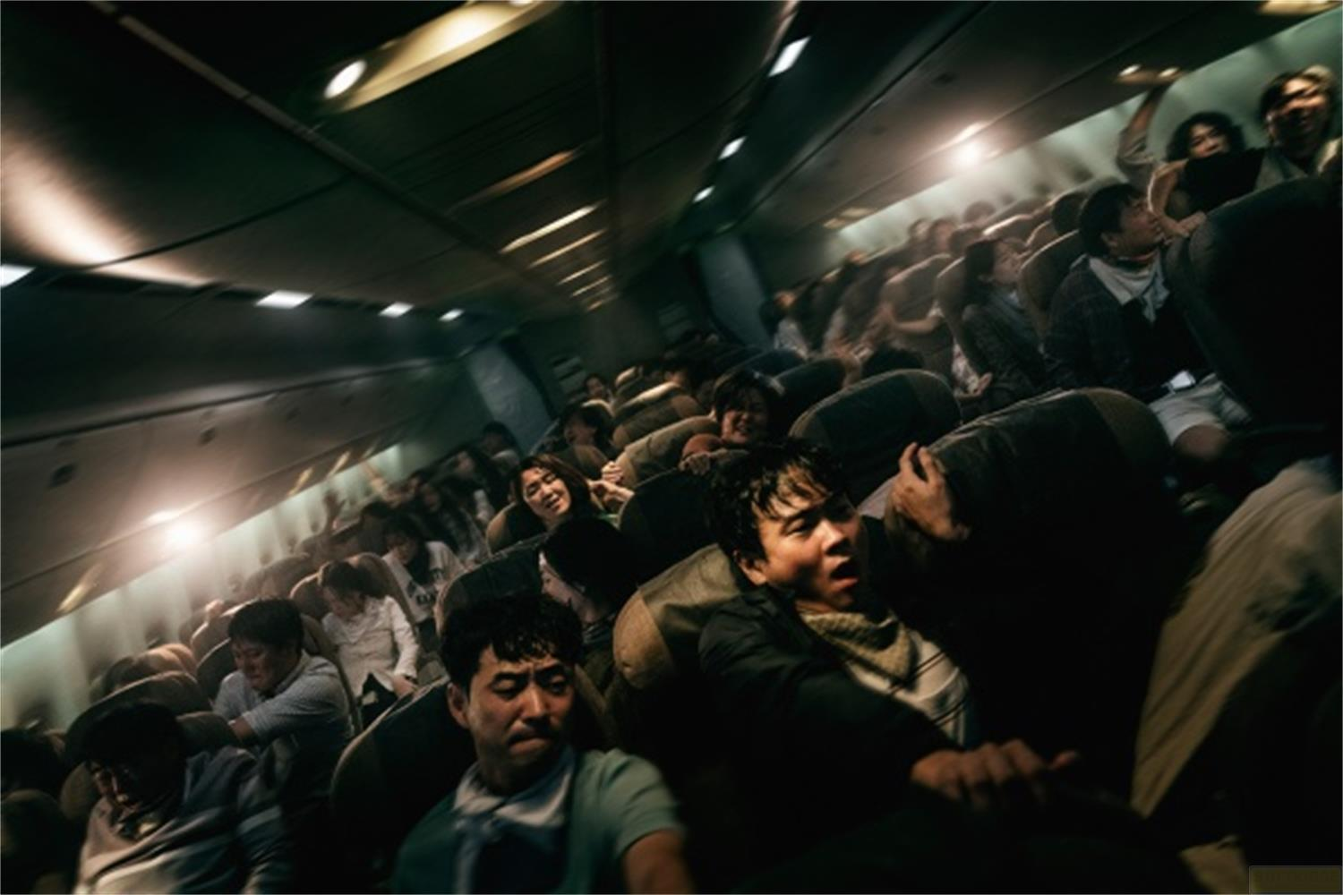 Gente stipata in una cabina di aereo, alcuni con espressioni di paura.