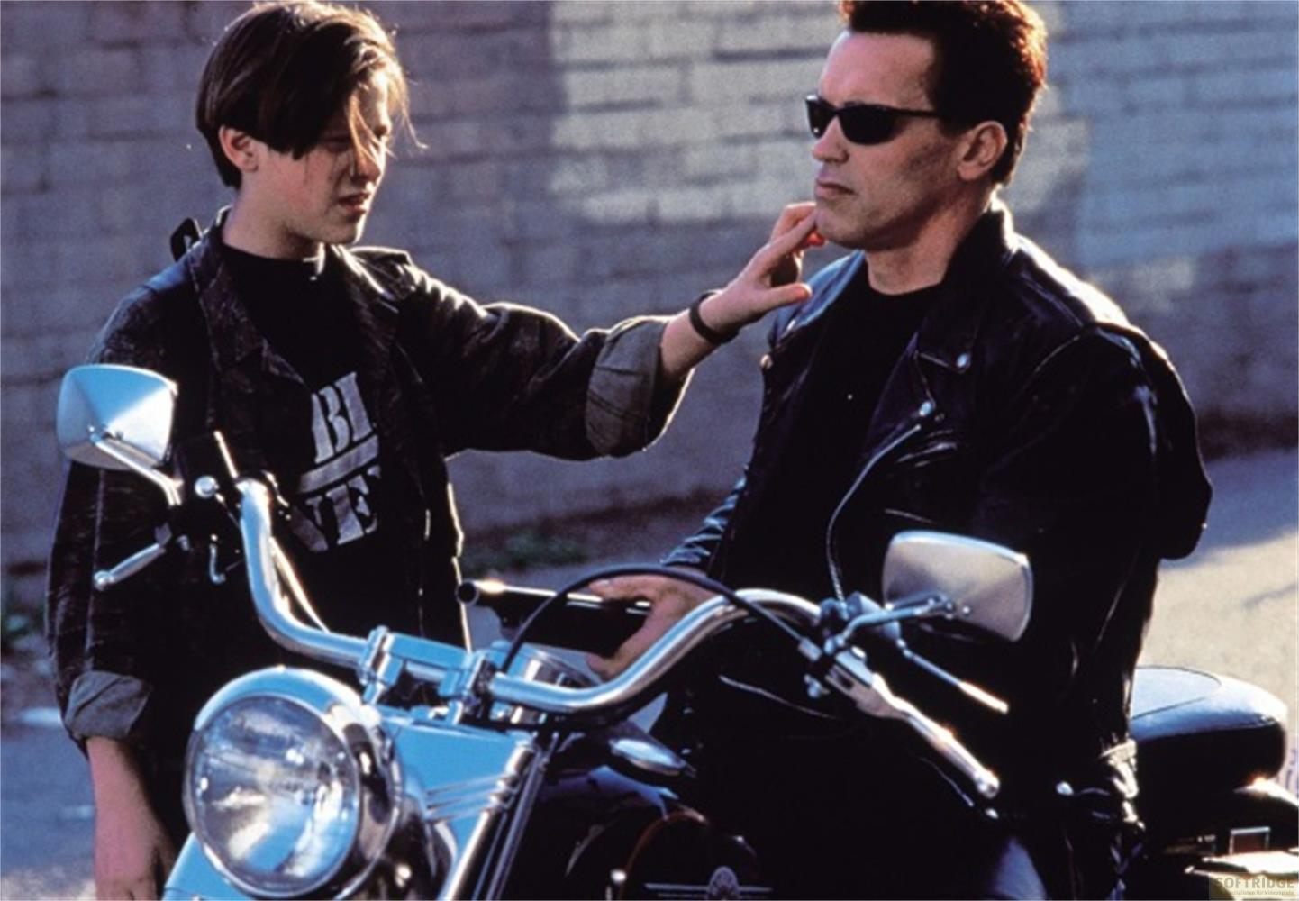 Ein Junge berührt das Kinn eines Mannes mit Sonnenbrille auf einem Motorrad.